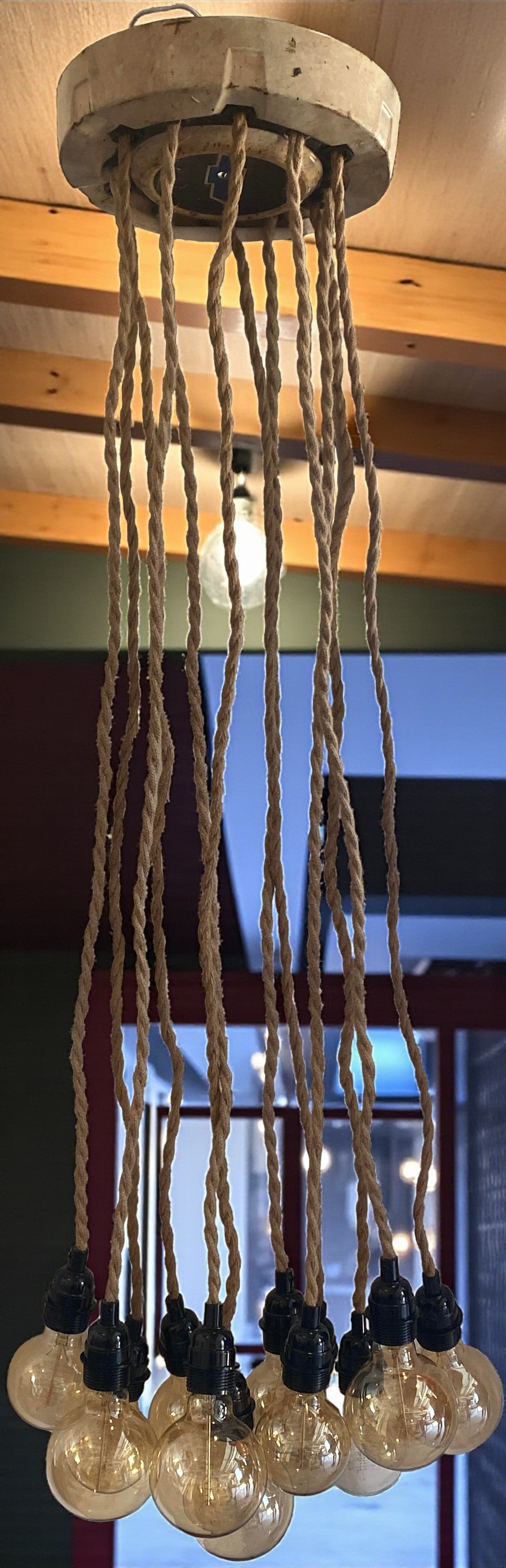 Industrial-style pendant light with multiple Edison bulbs hanging from vintage hubcap.