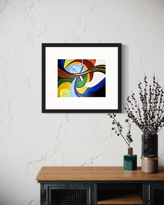 Framed abstract artwork on a white wall above a wooden table with decorative items.