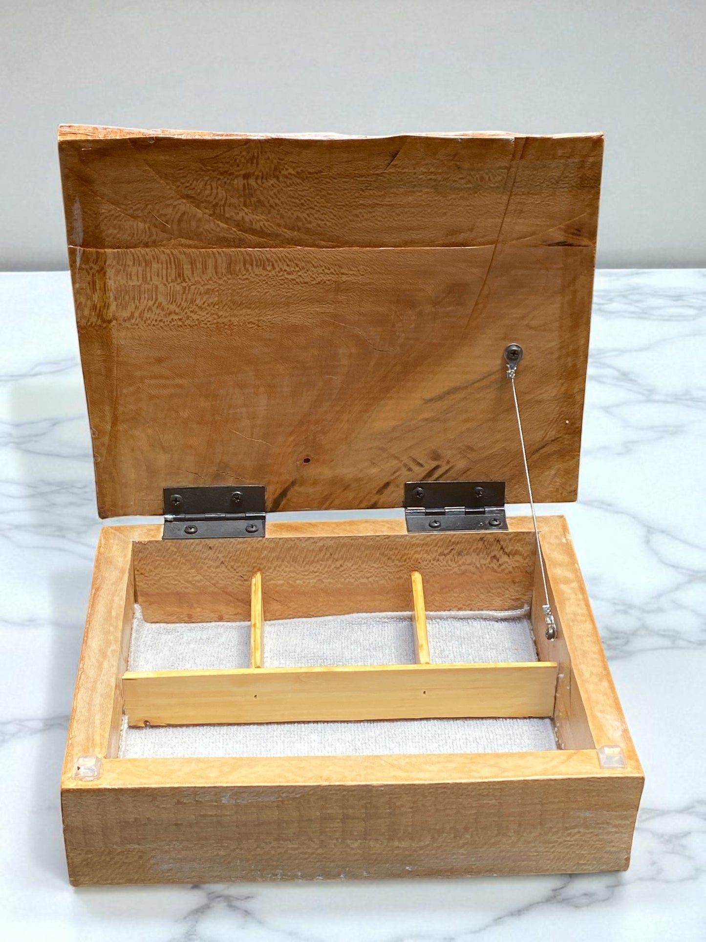 Wooden jewelry box with a hinged lid on a marble surface