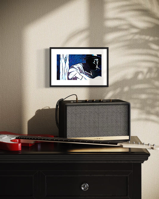 Black rectangular speaker on a wooden surface with a framed picture above it, against a textured wall.