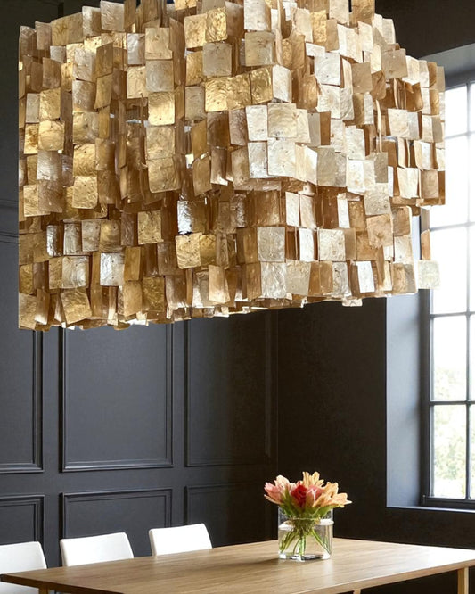Modern chandelier with geometric design in a room with a table and flowers.