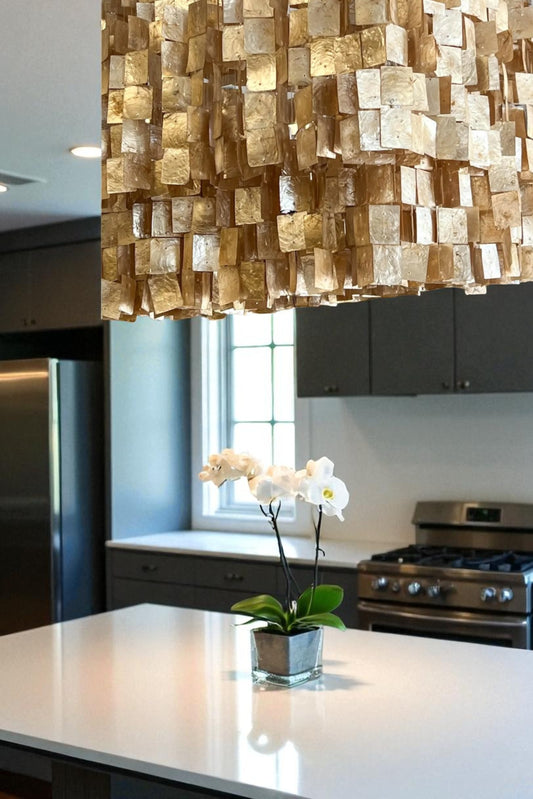 Modern kitchen with a decorative light fixture, white orchid, and stainless steel appliances.