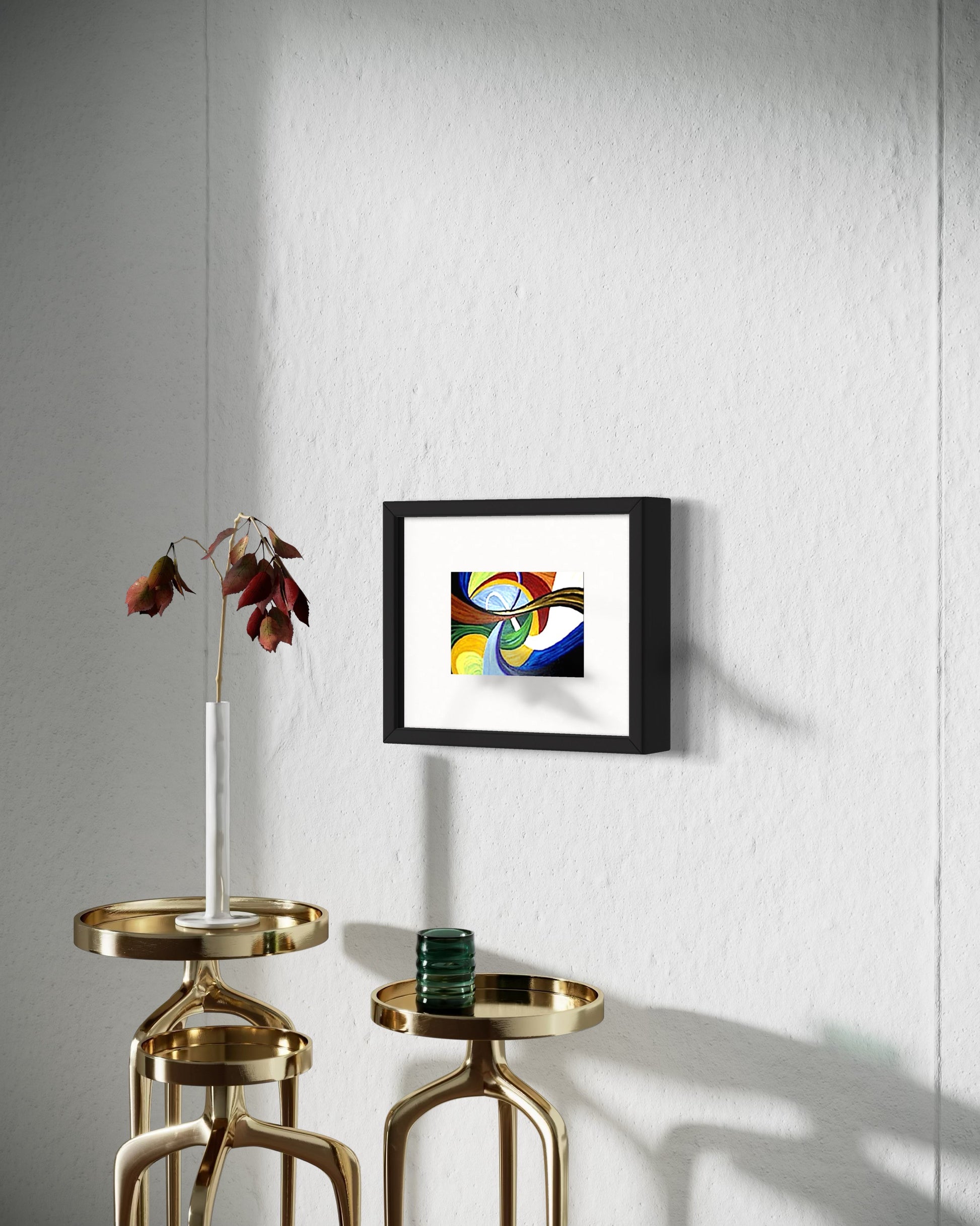 Framed abstract artwork on a wall with gold side tables and a vase.