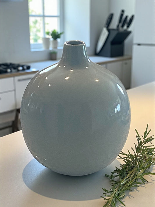 Light blue ceramic vase on a kitchen counter with greenery