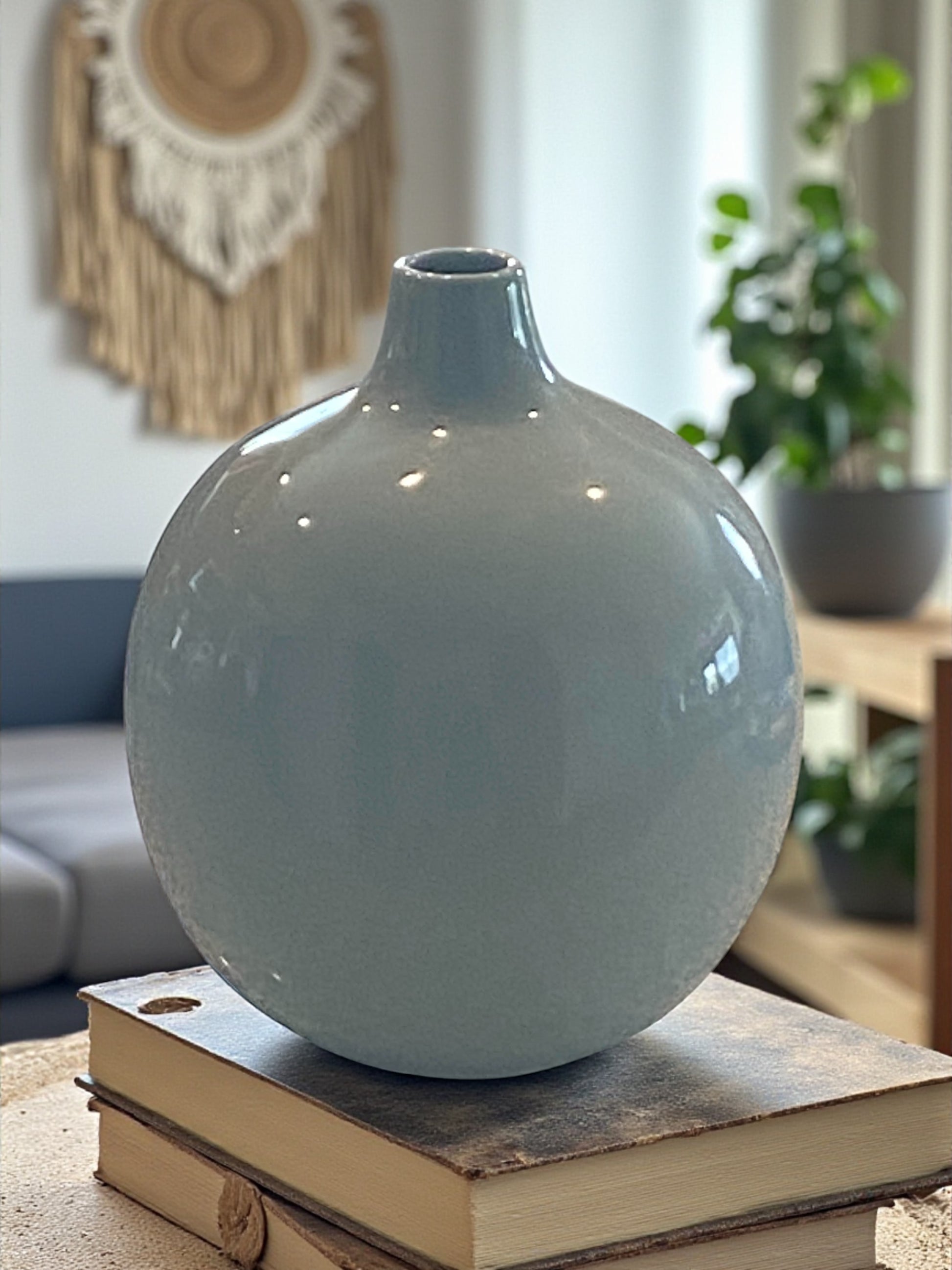 Blue ceramic vase on a stack of books in a living room setting