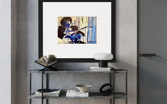 Framed artwork on a shelf with books and decor items against a gray wall.