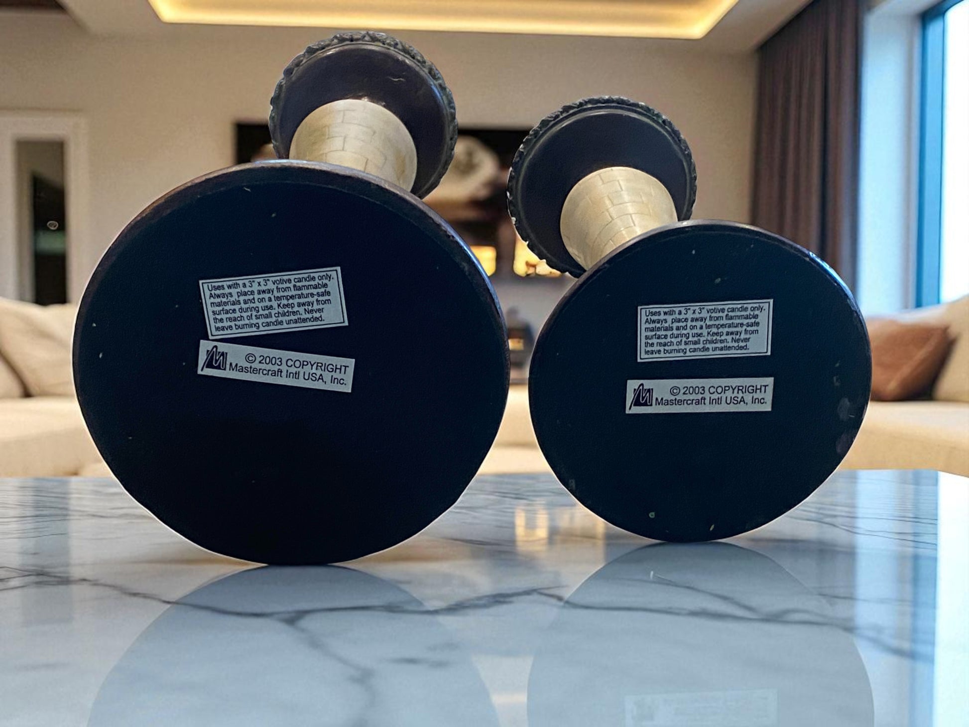 Two Metal and Marble Candle Holders with visible branding on a reflective surface.