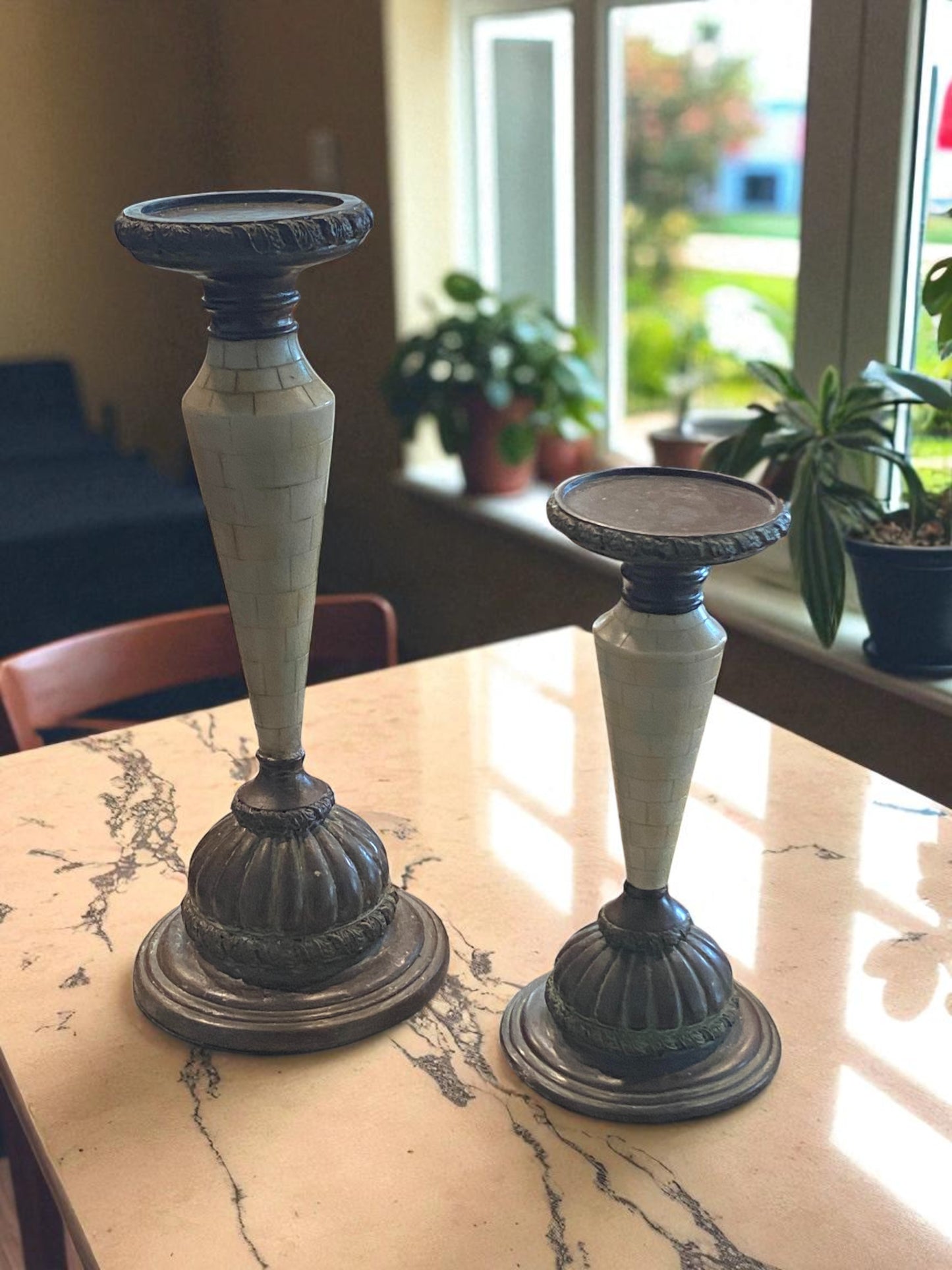 Two candle holders on a marble surface with a blurred indoor background