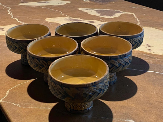 Set of six ceramic bowls with textured design on a stone surface