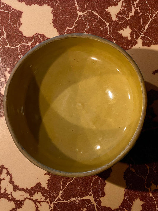 Green ceramic bowl on a marbled surface