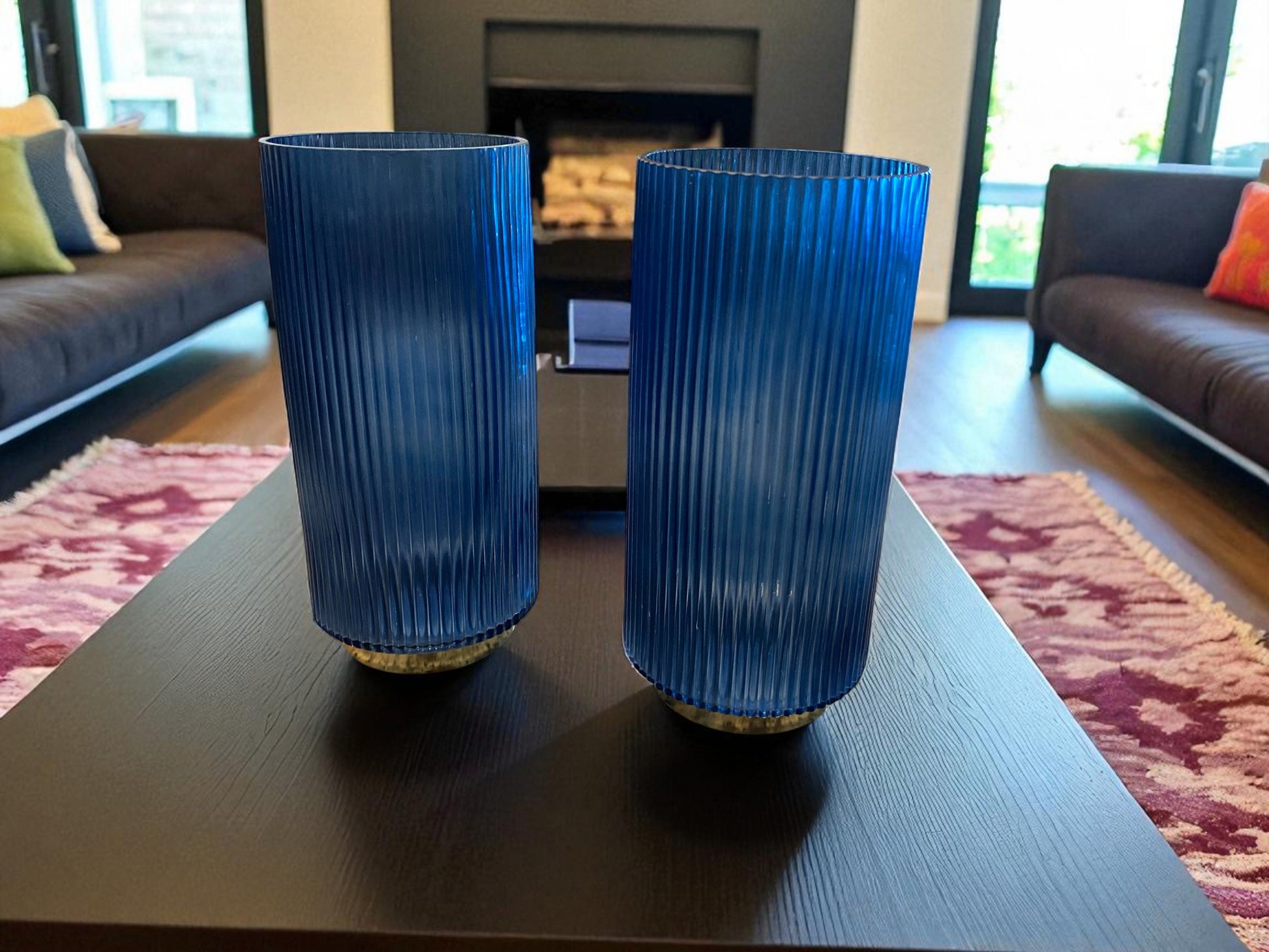 Two blue ribbed vases on a coffee table in a living room.