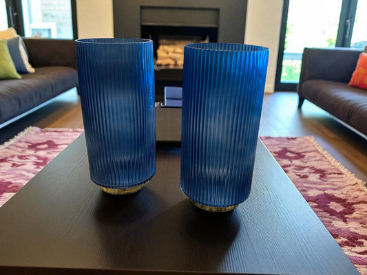 Two blue ribbed vases on a coffee table in a living room.