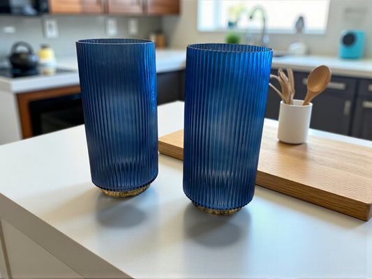Two blue ribbed vases on a kitchen counter with a blurred background