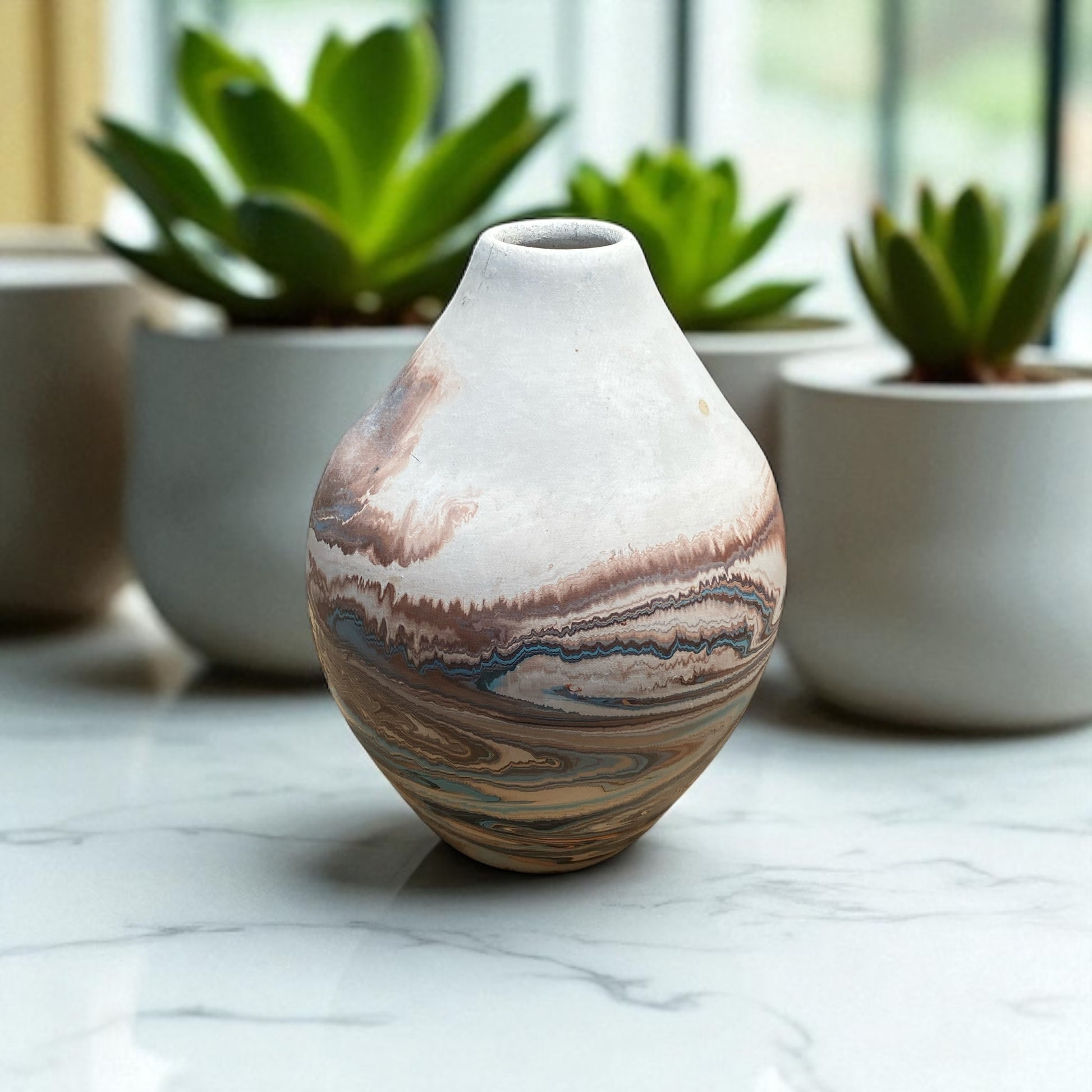 Marbled ceramic vase on a marble surface with plants in the background
